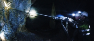 A worker operates a jackleg drill underground.