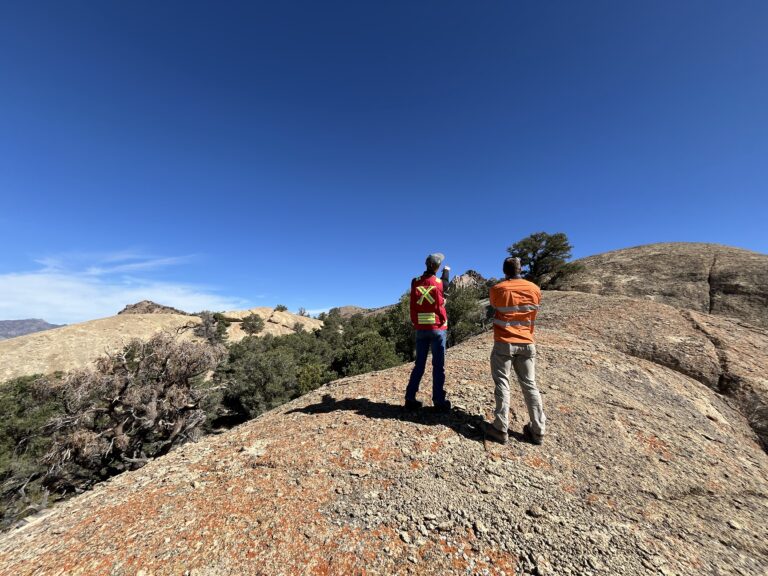A wide view of geologists standing on a volcanic rock outcrop.